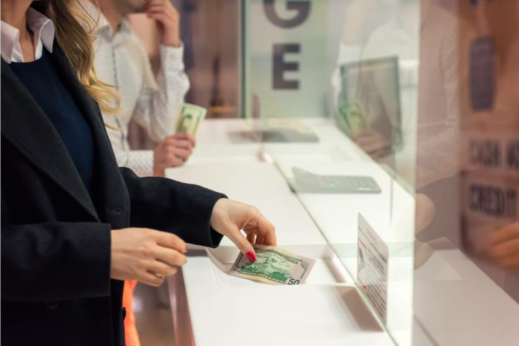 woman placing a 50 dollar bill underneath bulletproof counter area glass